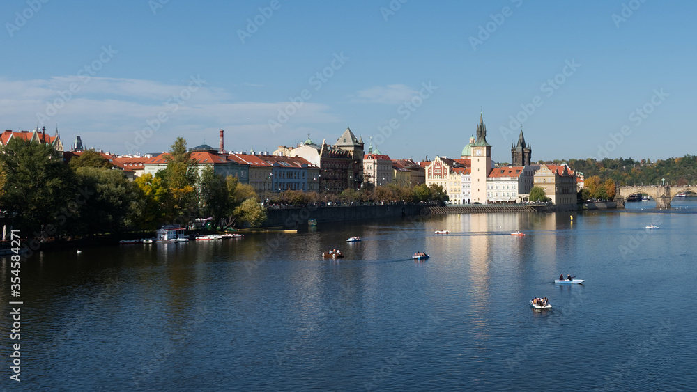 View of Prague from the bank of the Vltava. Tourists in boats on the river.