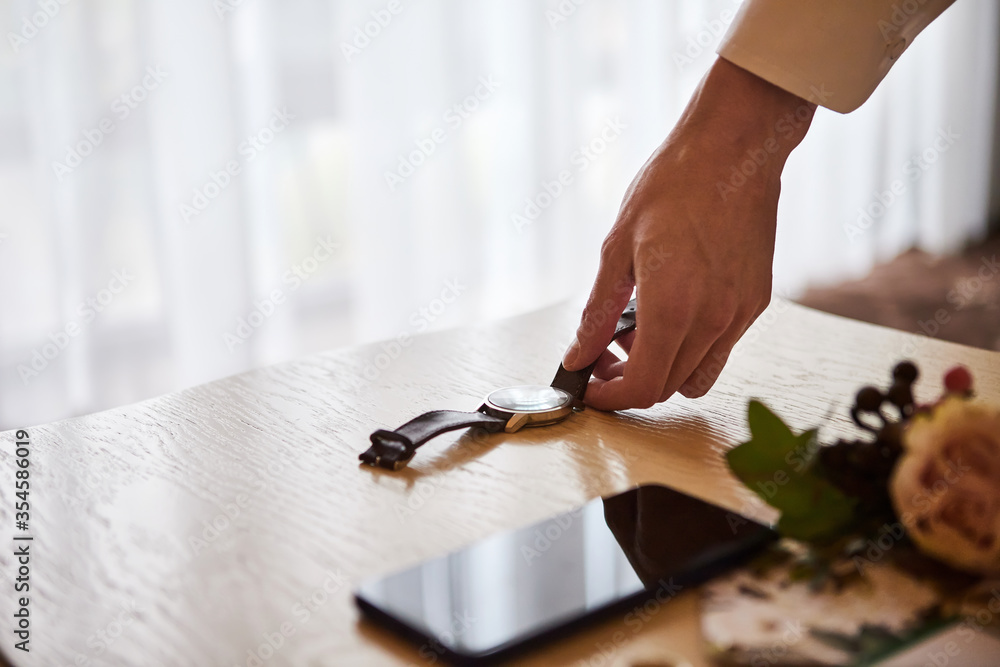 Obraz premium businessman checking time on his wrist watch, man putting clock on hand,groom getting ready in the morning before wedding ceremony. Men Fashion
