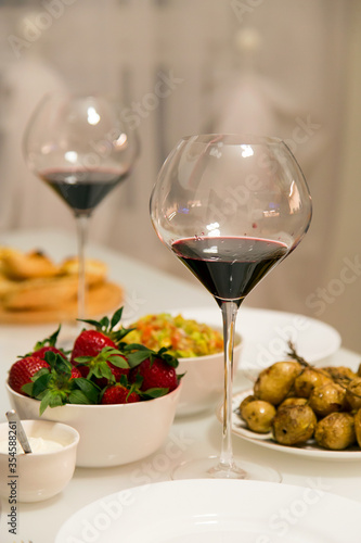 Table setting with red wine and strawberries.Vertically.