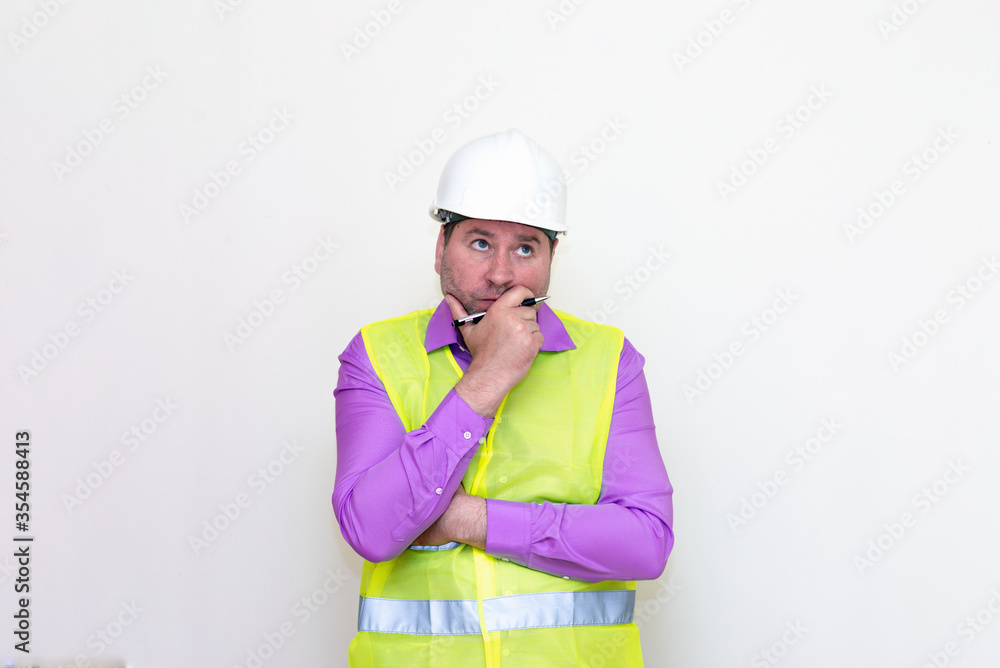Portrait middle age of caucasian worker wearing hard hat holding pen makes all kinds of grimaces on white studio background. Portrait middle age of caucasian worker wearing hard hat holding pen makes all kinds of grimaces on white studio background.