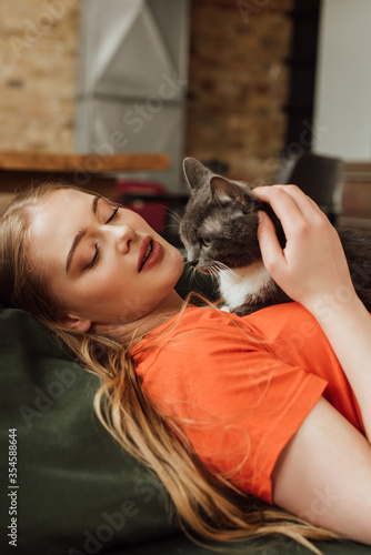 attractive young woman looking at cute cat in living room