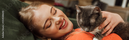 panoramic concept of cheerful woman looking at cute cat