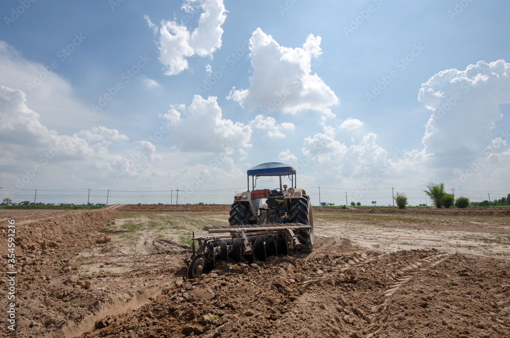 Fototapeta premium Thai farmer are reparation of rice field in the rainy season. The concept is that agricultural equipment is expensive. But cheap agricultural products.