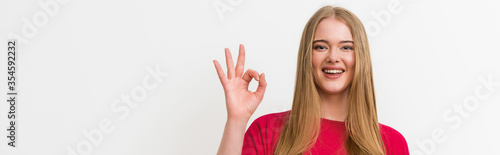 panoramic concept of cheerful woman showing ok sign isolated on white