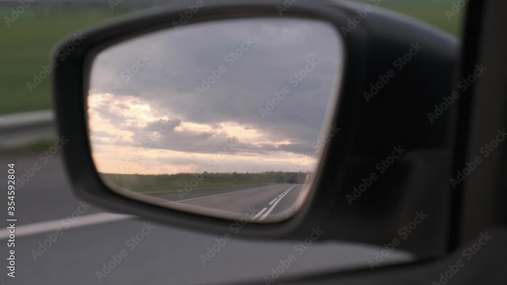 Close up view of highway reflection in car side view mirror. Travelling by car concept. Car moving along the road Close up view of highway reflection in car side view mirror. Travelling by car concept. Car moving along the road