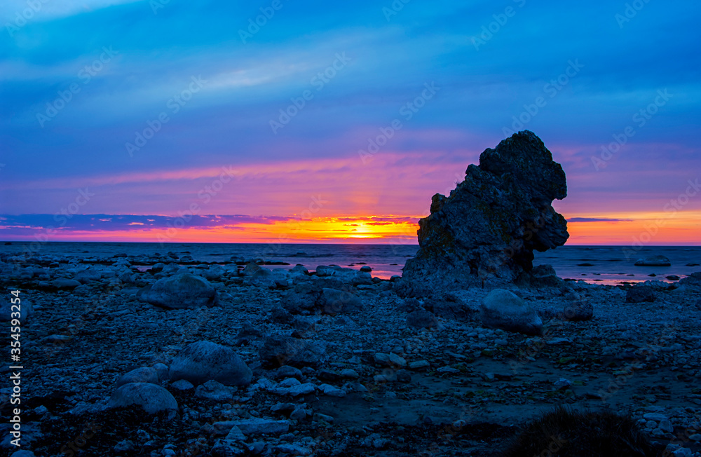 Limestone  stack with vibrant summer sunset over ocean, Sweden