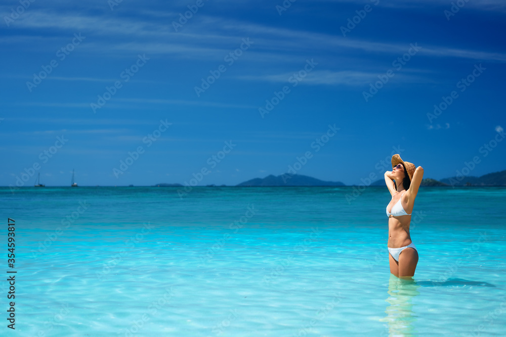 summer dreams. Beautiful sexy woman in white bikini and straw hat relax in turquoise sea water on tropical beach summer dreams. Beautiful sexy woman in white bikini and straw hat relax in turquoise sea water on tropical beach