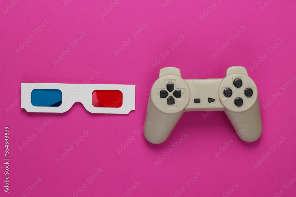 Anaglyph disposable paper 3d glasses and retro gamepad on pink background. Top view Anaglyph disposable paper 3d glasses and retro gamepad on pink background. Top view