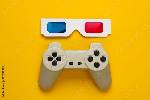 Anaglyph disposable paper 3d glasses and retro gamepad on yellow background. Top view