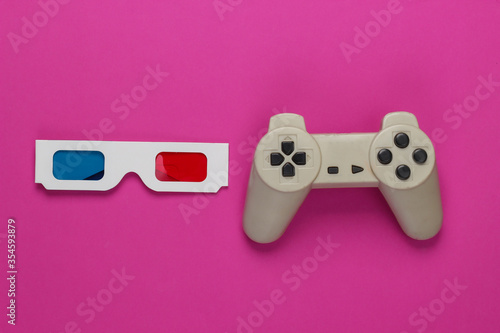 Anaglyph disposable paper 3d glasses and retro gamepad on pink background. Top view
