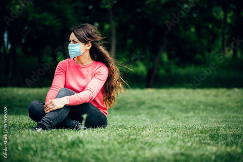 girl in a medical mask on the nature. Girl resting in the park after quarantine COVID-19
