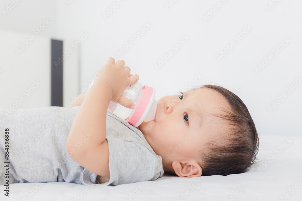 Close up of Adorable baby boy drinking milk from a bottle on the bed Close up of Adorable baby boy drinking milk from a bottle on the bed