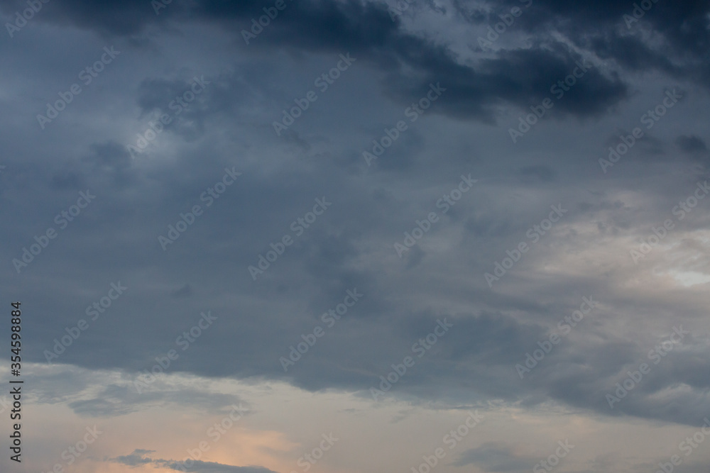 Beautiful dramatic gray and white clouds on blue sky, variety of shapes, silhouettes and shades at sunset time