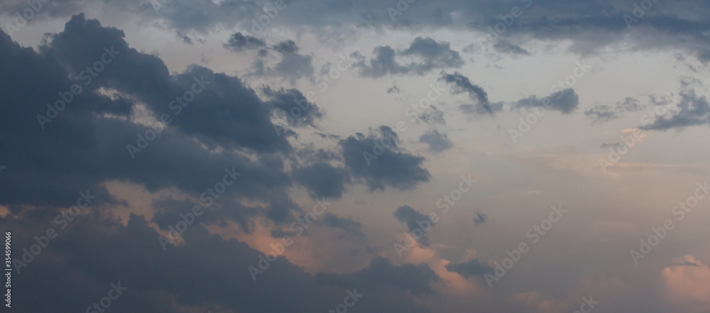 Beautiful dramatic gray and white clouds on blue sky, variety of shapes, silhouettes and shades at sunset time Beautiful dramatic gray and white clouds on blue sky, variety of shapes, silhouettes and shades at sunset time