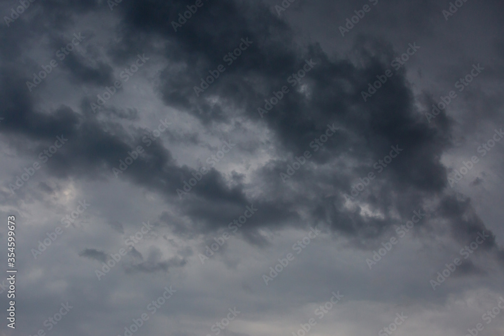 Beautiful dramatic gray and white clouds on blue sky, variety of shapes, silhouettes and shades at sunset time Beautiful dramatic gray and white clouds on blue sky, variety of shapes, silhouettes and shades at sunset time