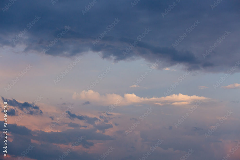Fototapeta premium Beautiful dramatic gray and white clouds on blue sky, variety of shapes, silhouettes and shades at sunset time