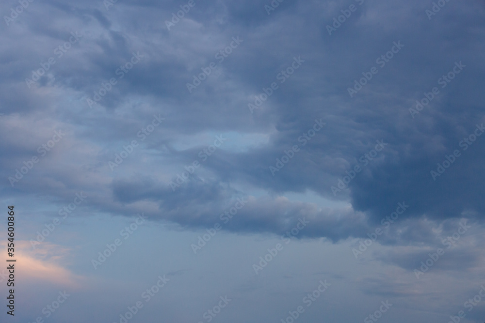 Beautiful dramatic gray and white clouds on blue sky, variety of shapes, silhouettes and shades at sunset time Beautiful dramatic gray and white clouds on blue sky, variety of shapes, silhouettes and shades at sunset time