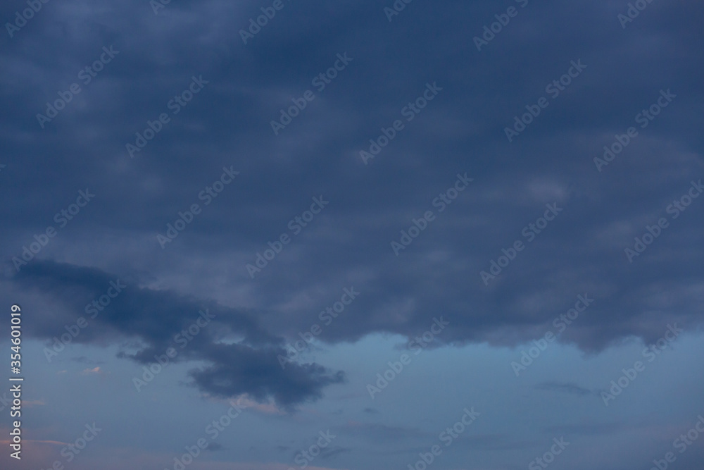 Beautiful dramatic gray and white clouds on blue sky, variety of shapes, silhouettes and shades at sunset time Beautiful dramatic gray and white clouds on blue sky, variety of shapes, silhouettes and shades at sunset time
