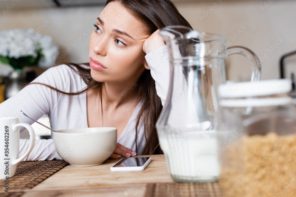 selective focus of sad girl near bowl, jug, cup and smartphone with blank screen selective focus of sad girl near bowl, jug, cup and smartphone with blank screen