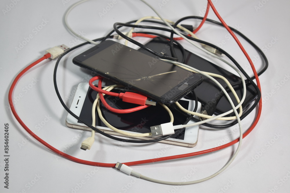 Closeup of old broken mobile phones with charging Cables and USB cables wires E-waste pollution Closeup of old broken mobile phones with charging Cables and USB cables wires E-waste pollution