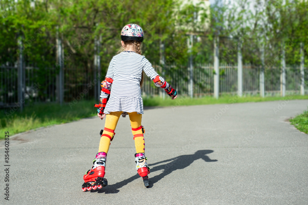 Roller skating little girl with protective gear outdoors