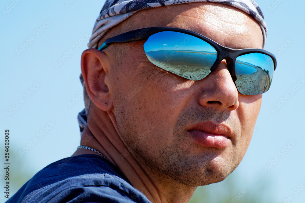A stranger walking along the Bay in mirrored glasses A stranger walking along the Bay in mirrored glasses