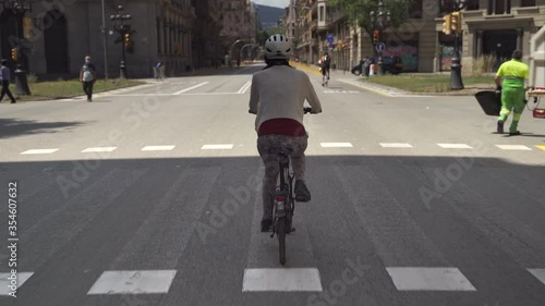 Woman is riding bicycle in the deserted Streets of Barcelona City due to Coronavirus Lockdown. Famous Via Laietana thoroughfare in Barcelona City Centre almost empty because Covid-19 crisis  photo