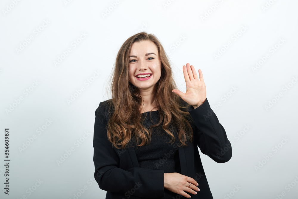 Shows a palm as greeting with open hand and five fingers, enjoying communication young attractive woman brunette in black t-shirt, sweater on white background Shows a palm as greeting with open hand and five fingers, enjoying communication young attractive woman brunette in black t-shirt, sweater on white background
