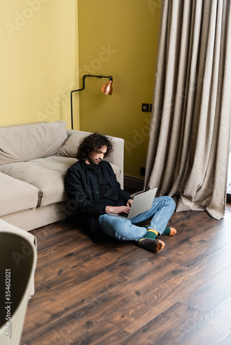 Selective focus of handsome man using laptop on floor at home © LIGHTFIELD STUDIOS