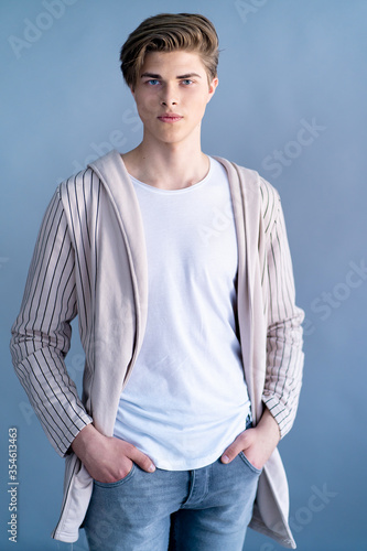 Handsome yong man in coat with stylish haircut on grey