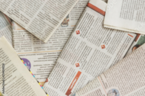 Lots of old newspapers on horizontal surface. Background texture, top view, blurred