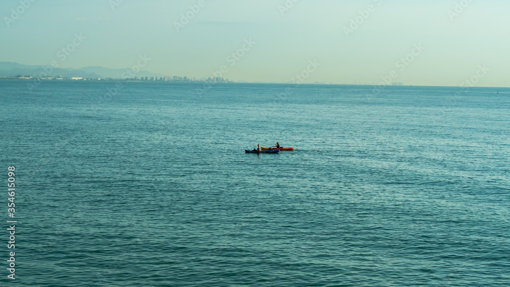 Two paddler kayak blue sea and the mountains behind