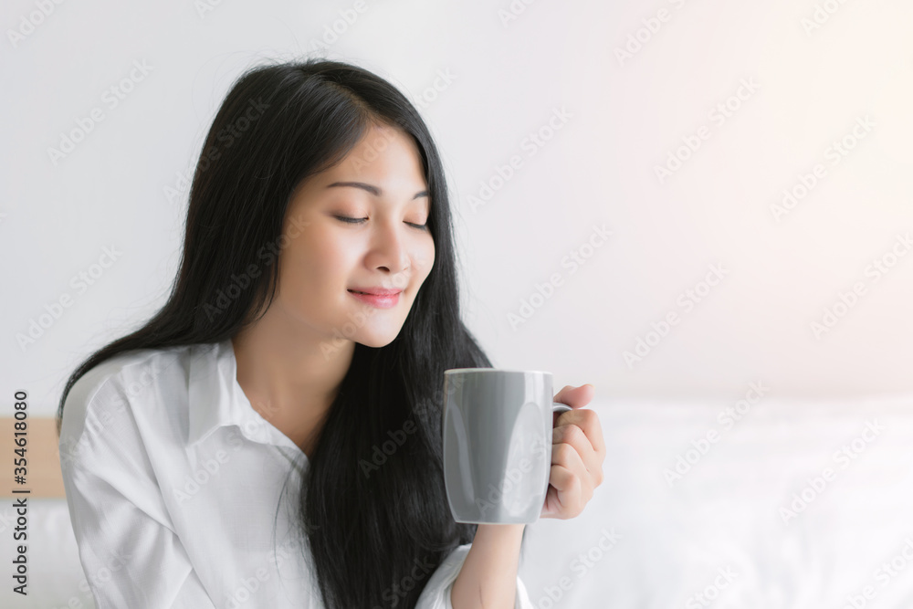 Beautiful young woman wake up and drinking coffee or tea in the morning at bedroom Beautiful young woman wake up and drinking coffee or tea in the morning at bedroom