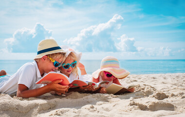 happy kids -boy and girls- read books on beach, summer reading on vacation