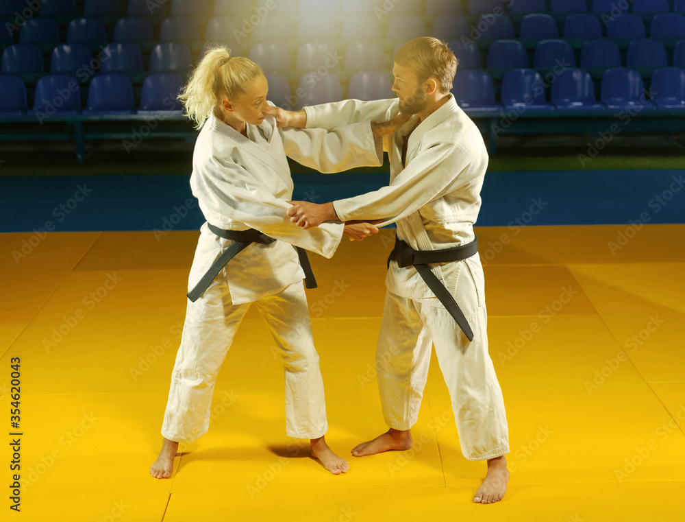Martial arts. Sparing Portners. Sport man and woman in white kimono train judo captures in the sports hall Martial arts. Sparing Portners. Sport man and woman in white kimono train judo captures in the sports hall