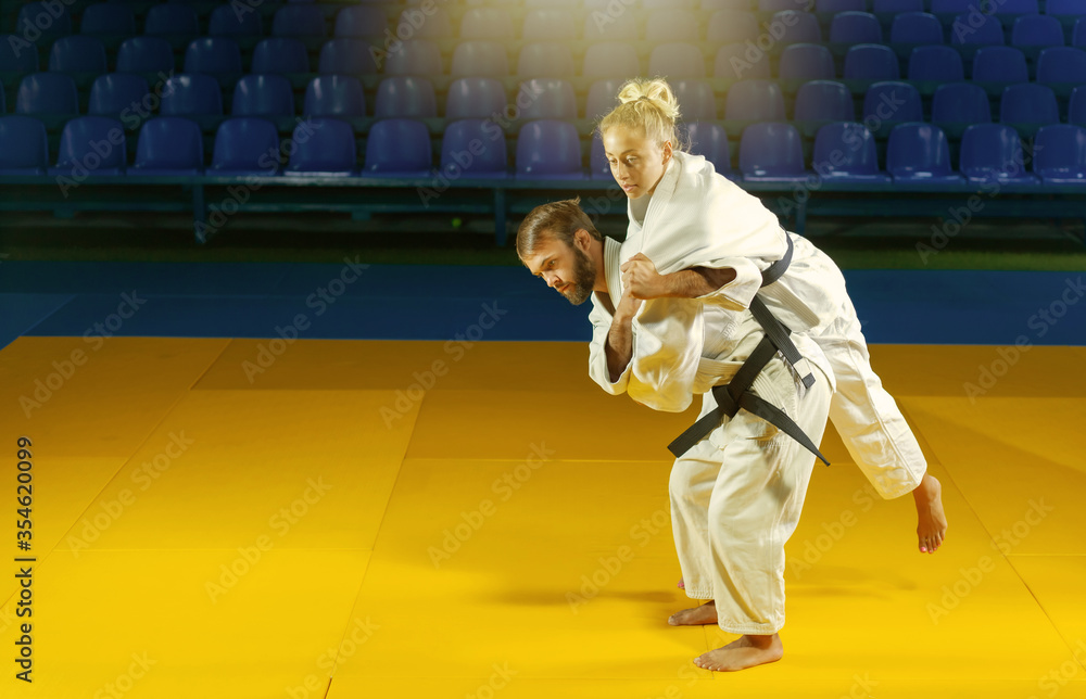 Martial arts. Sparing Portners. Sport man and woman in white kimono train judo throws and captures in the sports hall