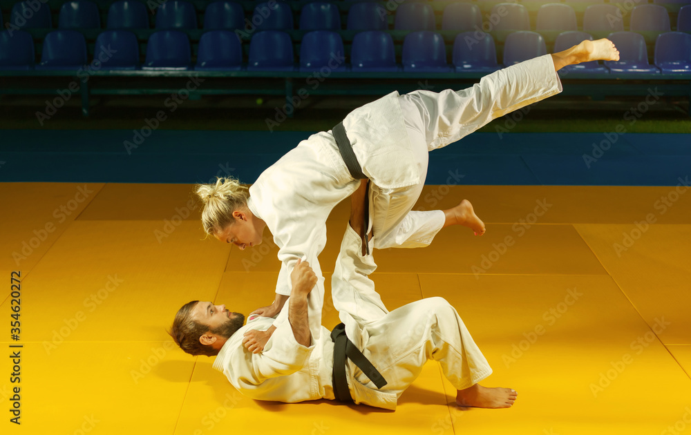 Martial arts. Sparing Portners. Sport man and woman in white kimono train judo throws and captures in the sports hall Martial arts. Sparing Portners. Sport man and woman in white kimono train judo throws and captures in the sports hall