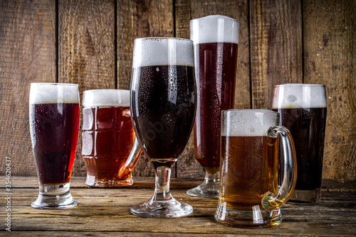 Different sorts of craft beer on wooden bar background. Set of various beer glasses and mugs. Beer tasting concept