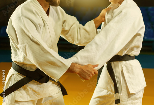 Martial arts. Sparing Portners. Sport man and woman in white kimono train judo captures in the sports hall. Crop photo