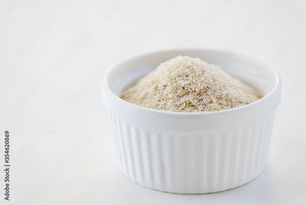 Psyllium husk in a white bowl. Natural dietary fiber for bowel regulation. Psyllium husk in a white bowl. Natural dietary fiber for bowel regulation.
