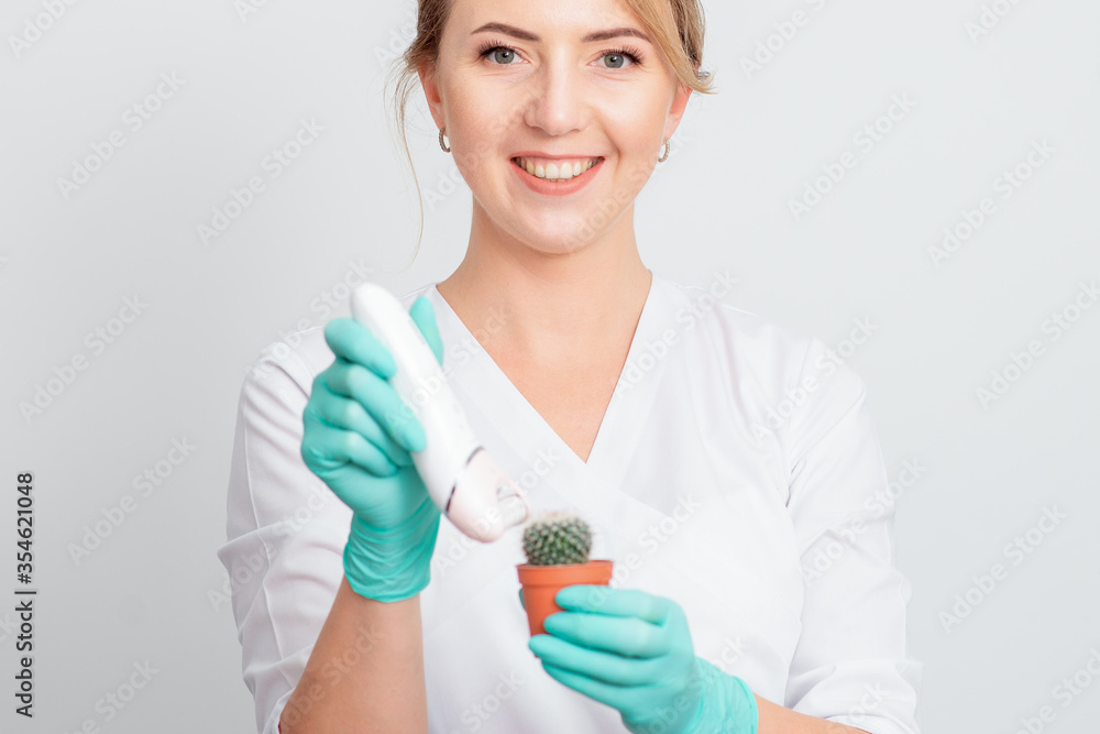 Cosmetologist is shaving green cactus in a brown pot with electric epilator wearing gloves smiling on white background. Concept of depilation, epilation and removal hair. Cosmetologist is shaving green cactus in a brown pot with electric epilator wearing gloves smiling on white background. Concept of depilation, epilation and removal hair.