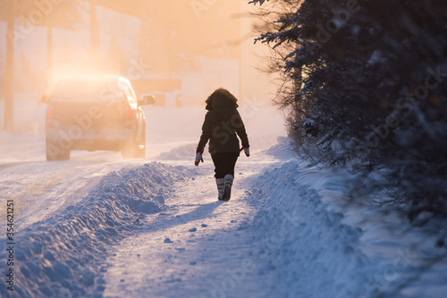 A woman dressed for extreme cold walks through Old Town at sunset in Yellowknife, Northwest Territories, Canada. photo