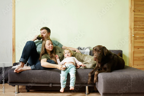 Young happy family with little toddler kid and dog labrador retriever at home on the couch, stay home concept