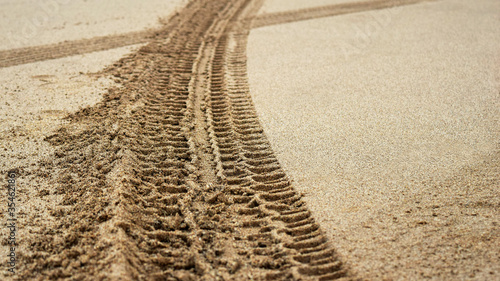 Tire prints on beach sand left by off road vehicle. Abstract background and pattern.