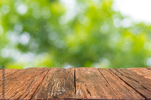 Empty old wooden table in front of blurred bokeh of natural sunlight and tree in garden background. Can be used for display or montage for show your products.