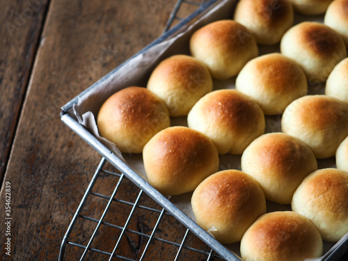 Small dinner bread rolls in baking tin on wooden background photo