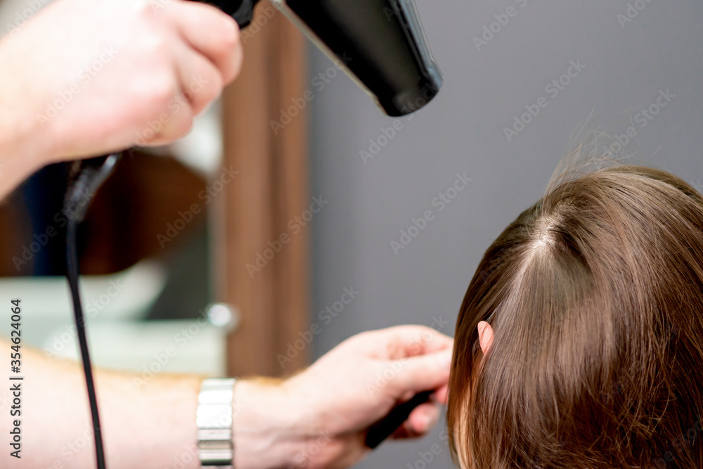 Fototapeta premium Hairdresser's hands blow drying hair of woman at the beauty salon.