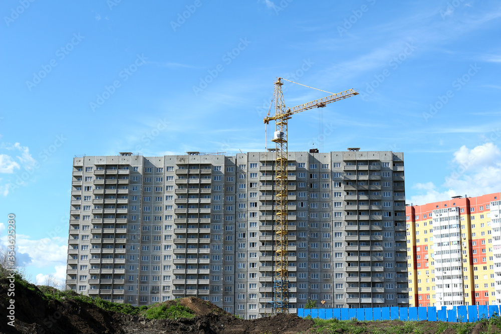 Photo of the construction of a house in a new residential complex in a picturesque natural countryside. Crane at a construction site. Photo of the construction of a house in a new residential complex in a picturesque natural countryside. Crane at a construction site.