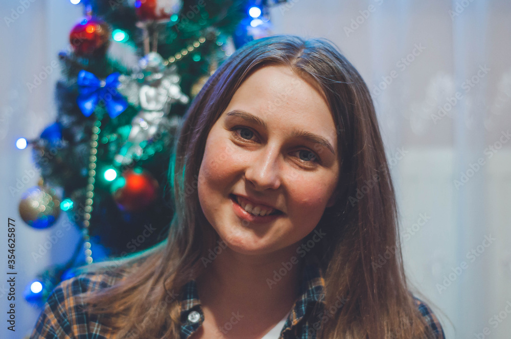 girl in a checkered shirt sitting near the Christmas tree girl in a checkered shirt sitting near the Christmas tree