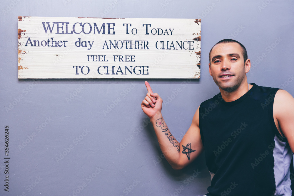 Latino boy pointing motivational poster in English on wall,